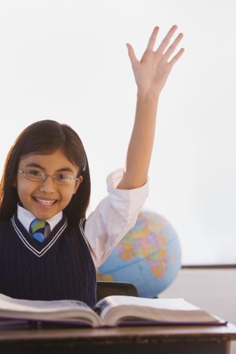 BLD026198 Young Hispanic girl raising hand in classroom